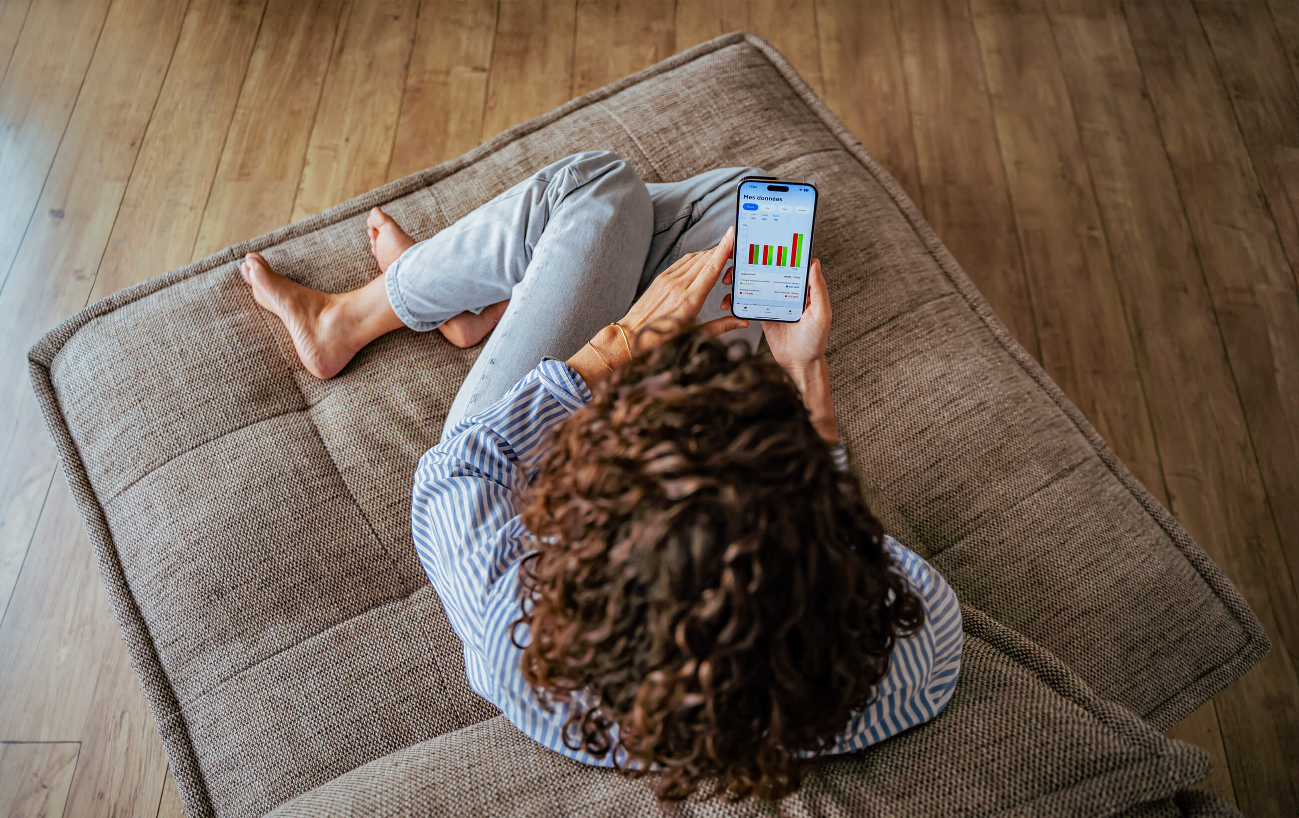Femme assise sur son canapé sur l'application EDF solutions solaires