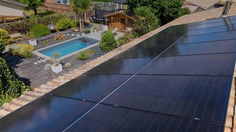 photo d'une maison avec vue sur le toît et son panneau solaire avec une piscine en fond